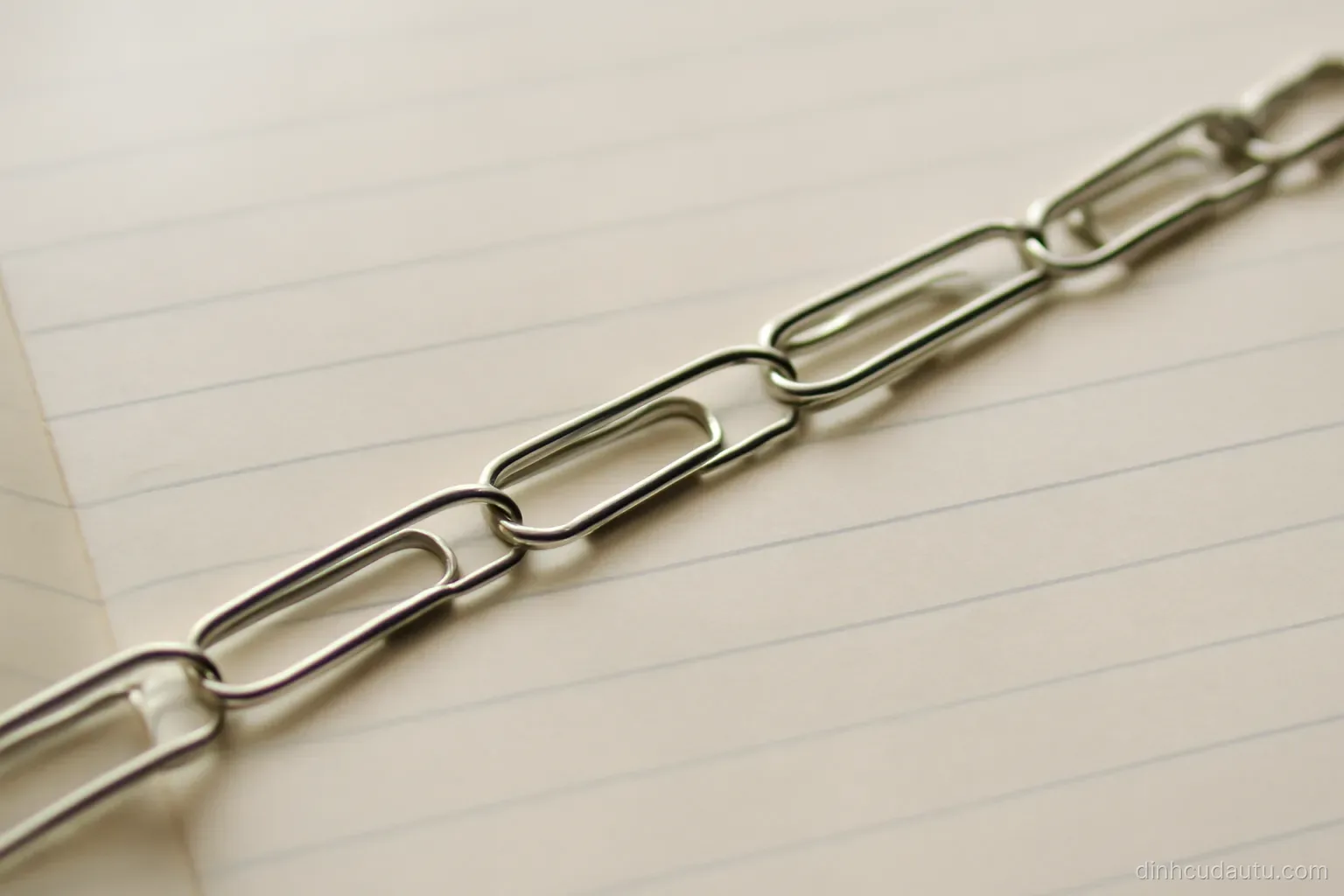 a row of paper clips linked together stretching across a plain notebook page